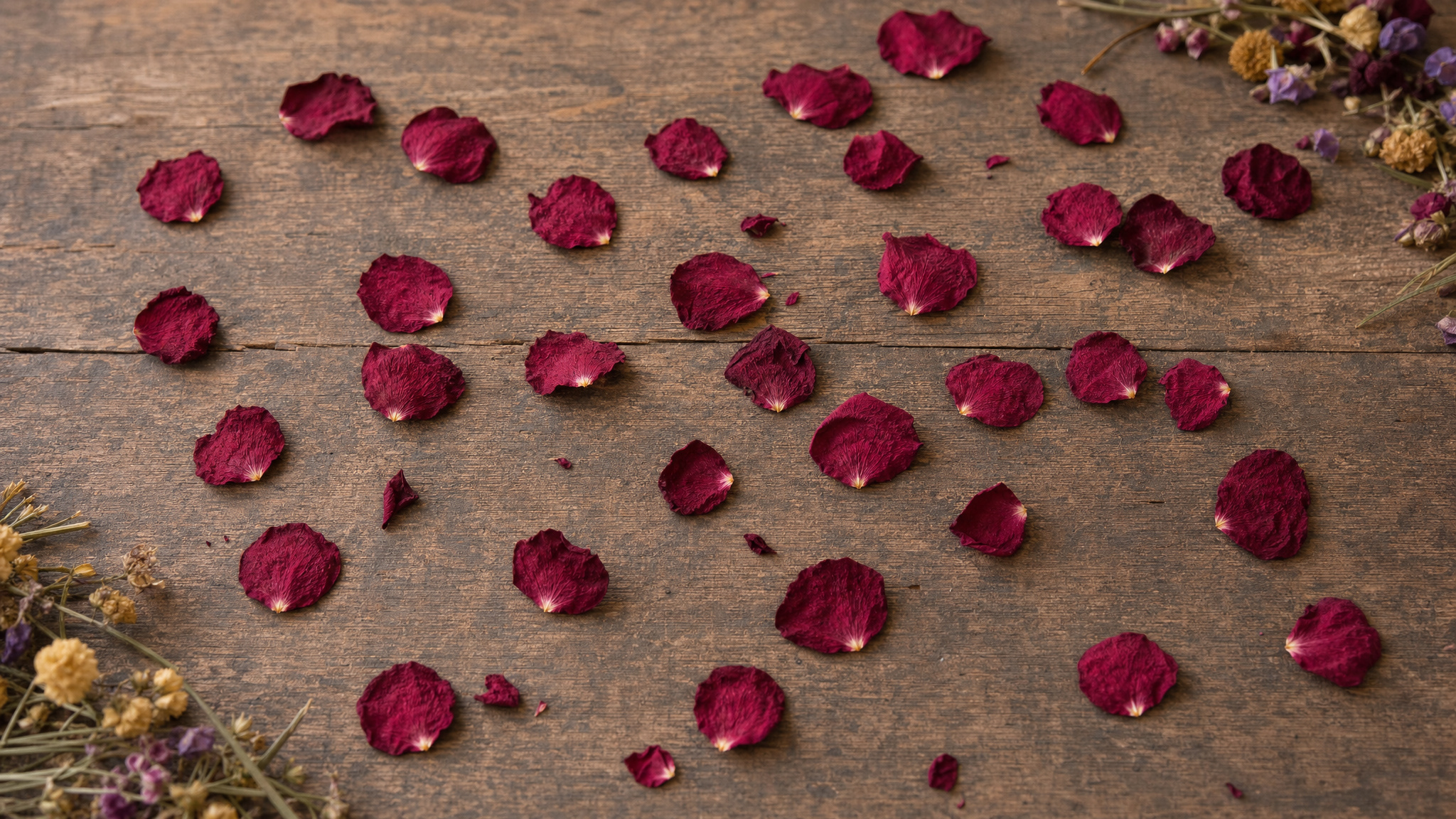 Freeze-dried red rose petals scattered across a florist's wooden worktable
