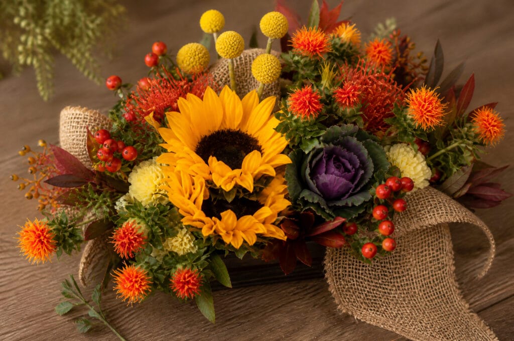 Carnations and small pumpkins placed into a rustic fall floral arrangement to hide the mechanics