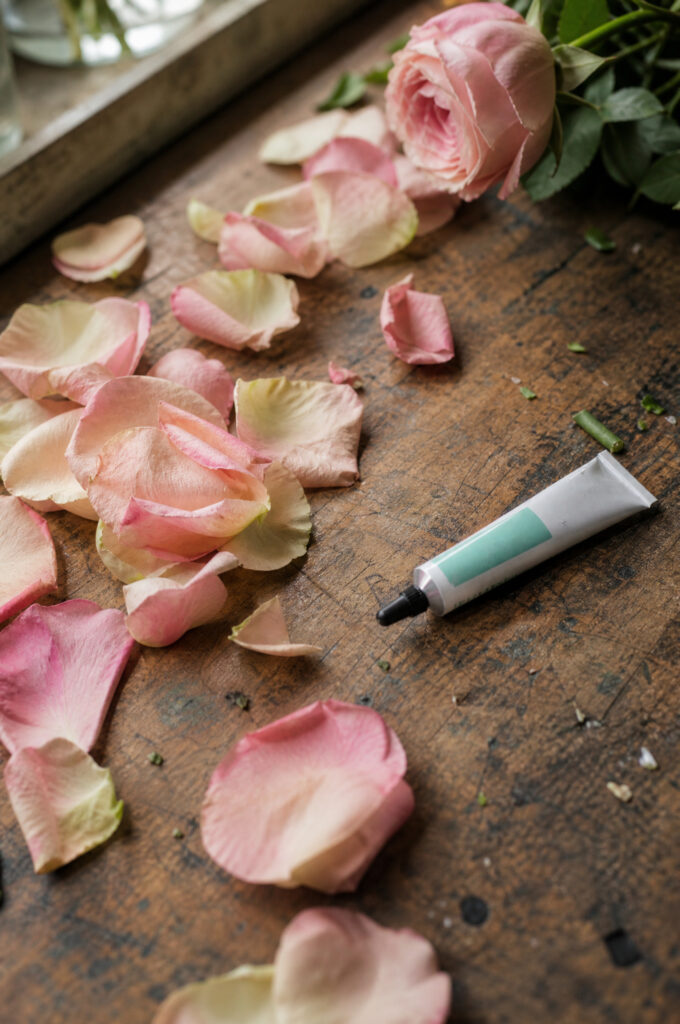 Loose rose petals and a bottle of floral adhesive laid out for practice on a worktable