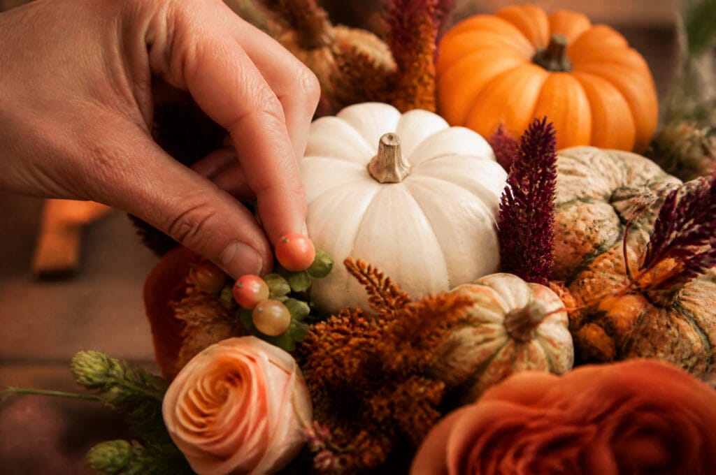 Coffee beans being tucked into gaps between gourds in a cornucopia arrangement