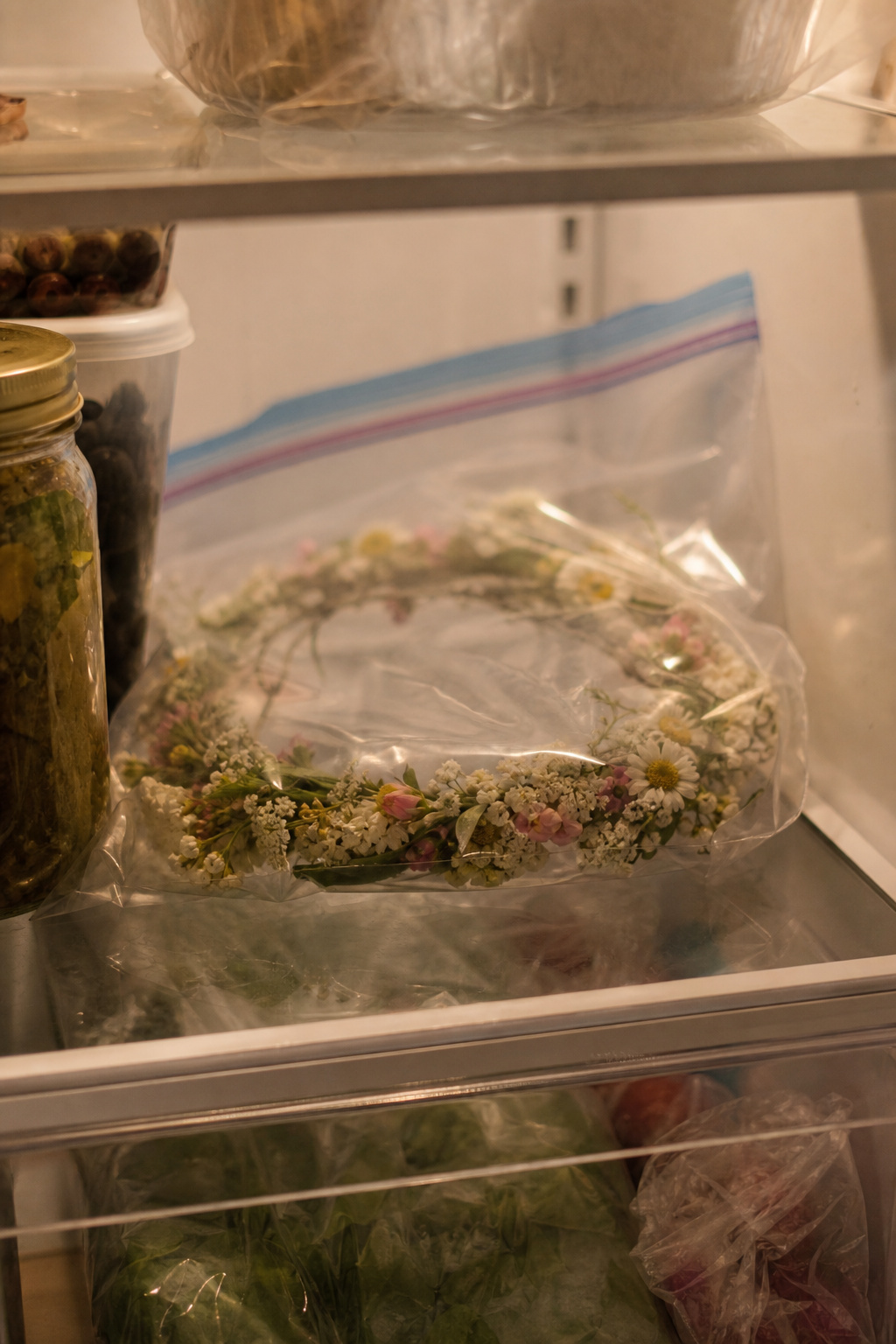 Floral headpiece in a sealed zip-lock bag resting on a refrigerator shelf