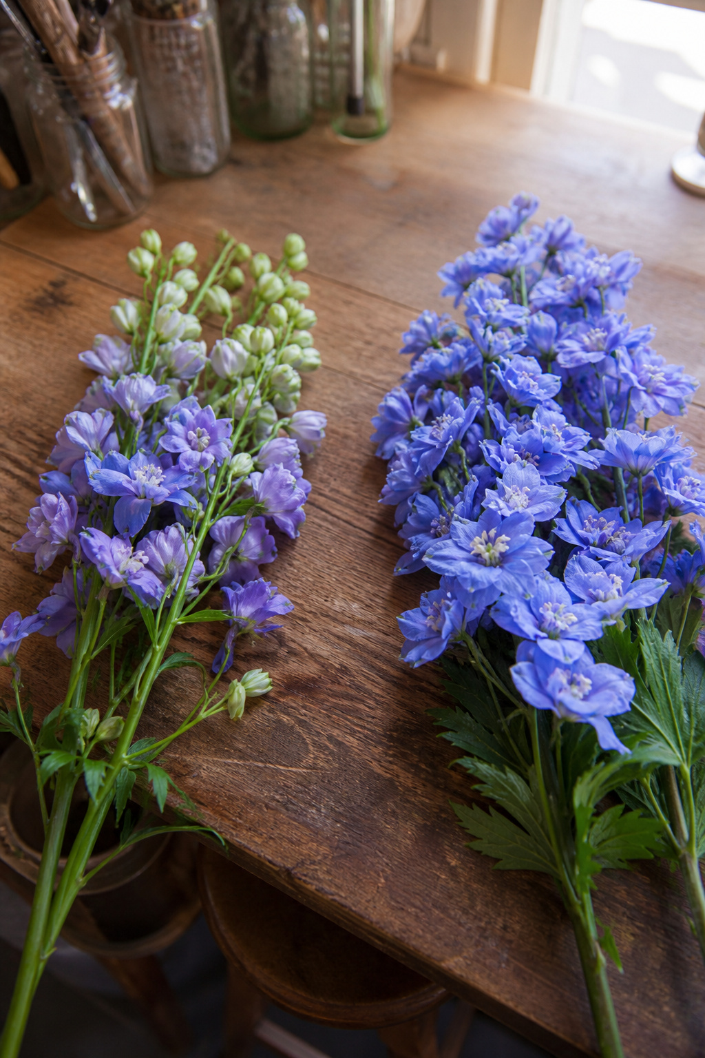 Silk flowers and fresh flowers side by side on a florist worktable for comparison