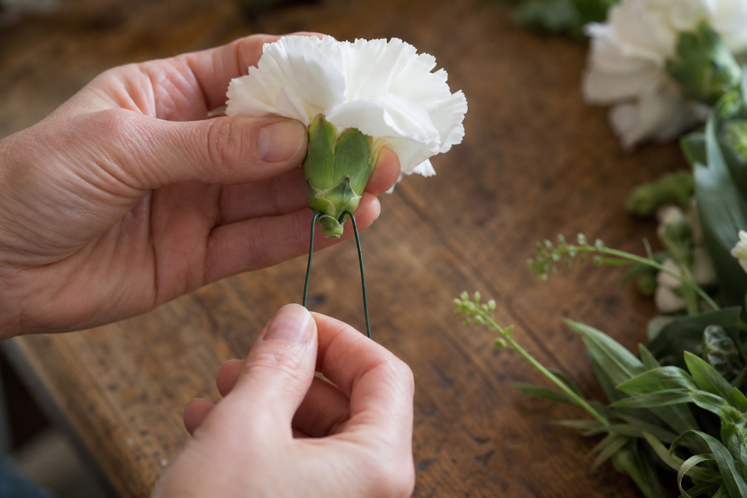 Florist demonstrating the pierce method for wiring a carnation for a corsage