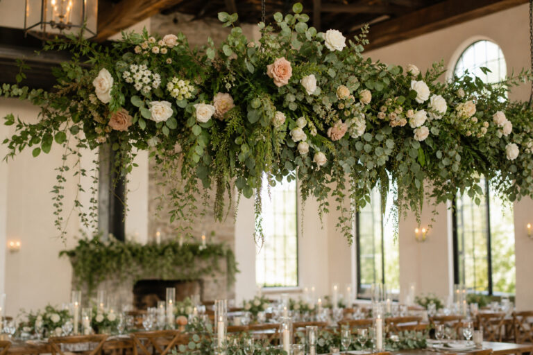 Hanging floral installation with roses and eucalyptus above a reception table