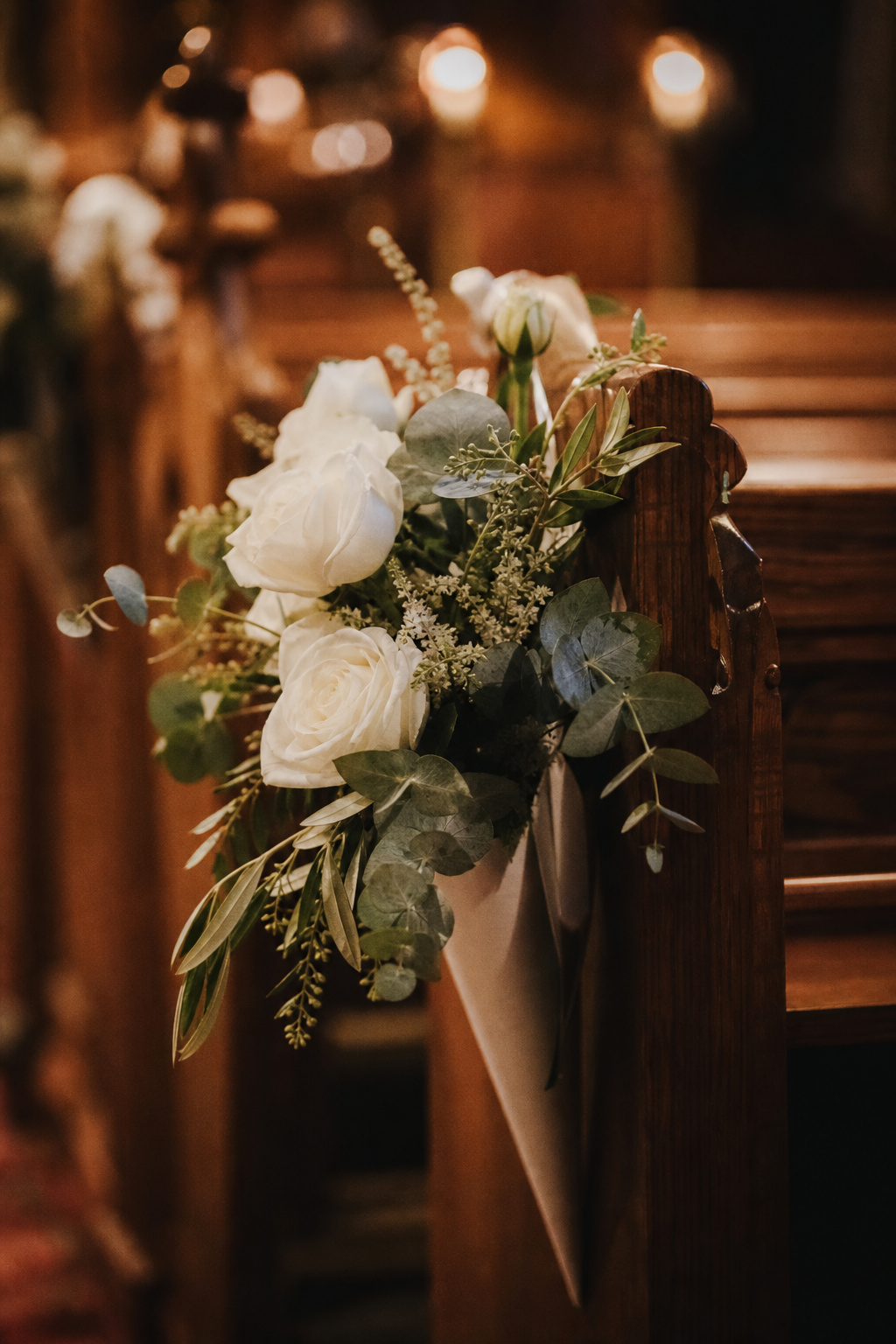 Well-designed pew end flower arrangement on a wooden church bench