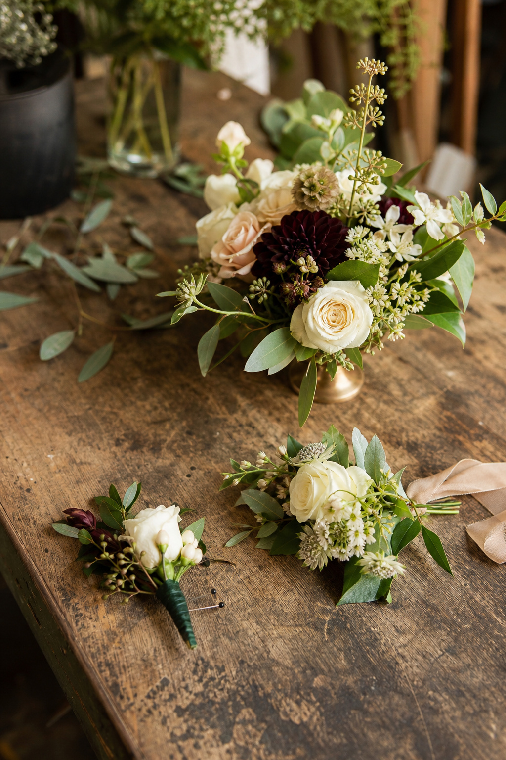Small floral accents including a boutonniere and corsage arranged on a florist worktable