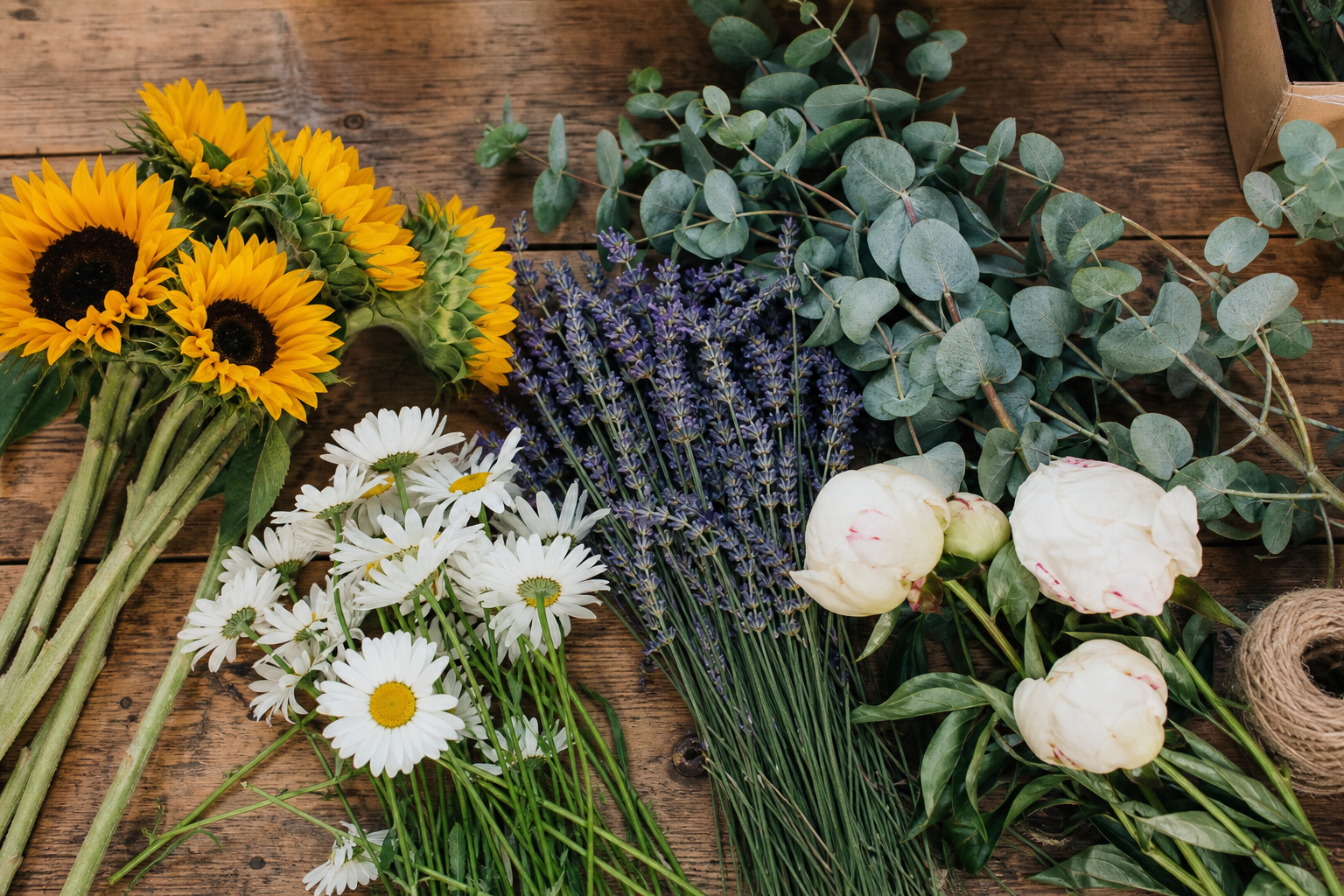 Sunflowers, daisies, lavender, and eucalyptus laid out on a florist worktable