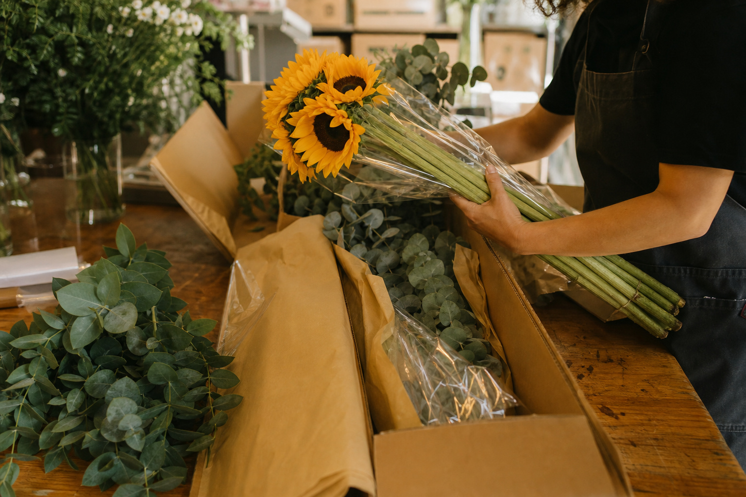 Boxes of fresh cut flowers being unpacked on a florist worktable