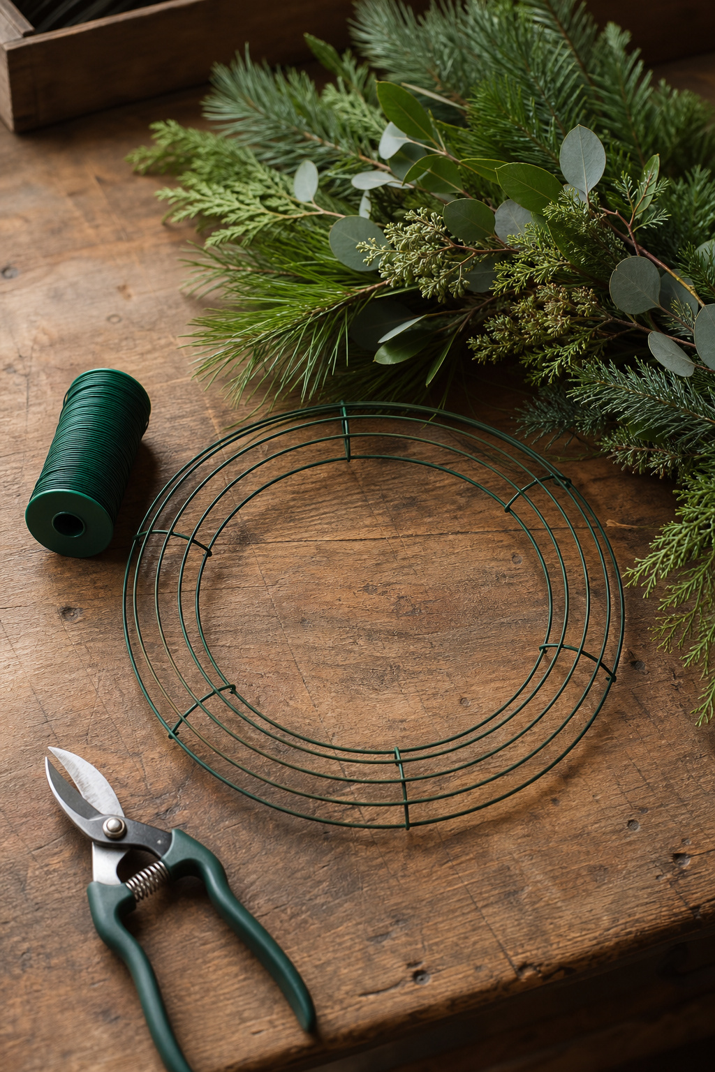Wire wreath form, paddle wire, and floral shears laid out on a wooden worktable