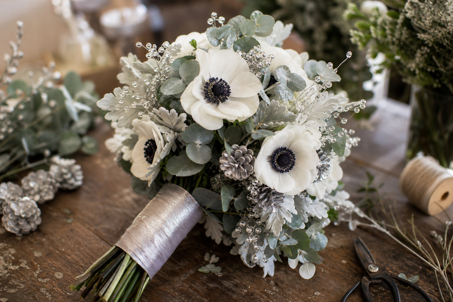 Silver and white winter wedding bouquet with white anemones, dusty miller, and crystal accents
