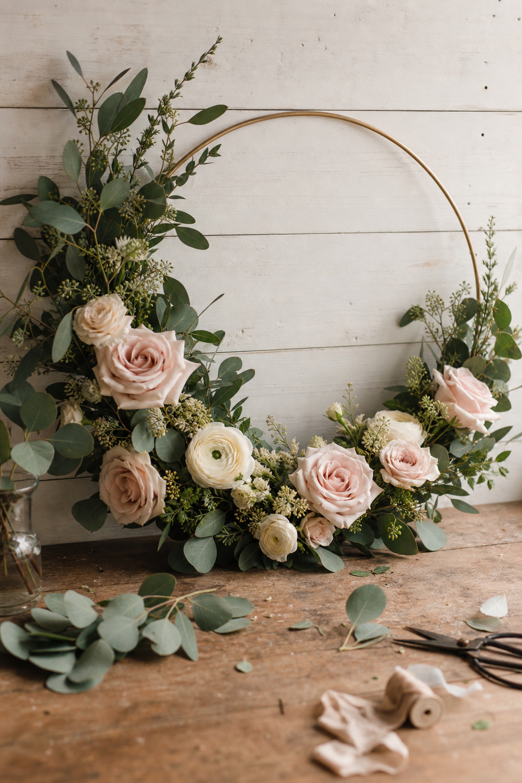 Floral hoop using silk blooms with fresh eucalyptus foliage on a wooden backdrop