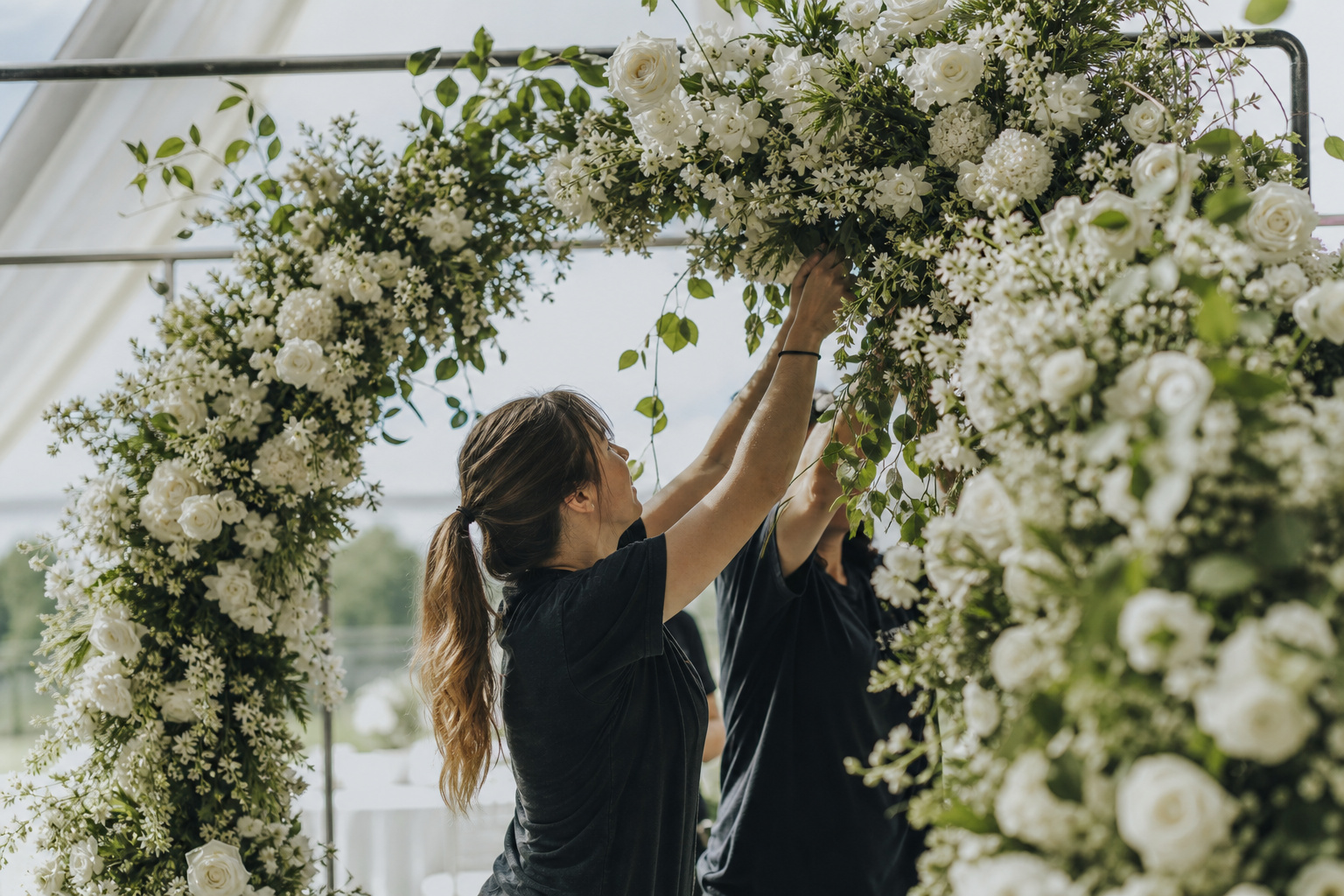 Outdoor floral arch installation with secured flower clusters in natural daylight