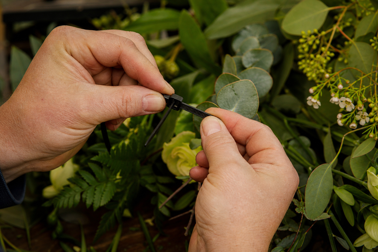 Florist demonstrating the double-lock zip tie method for heavy floral installations