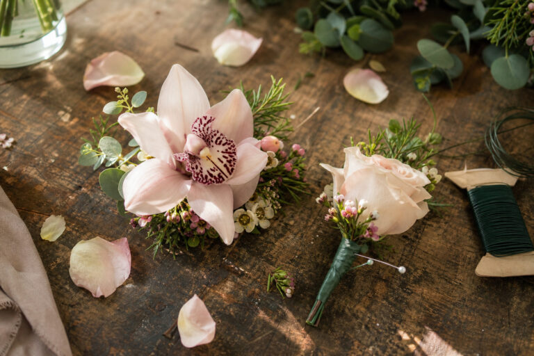 Wedding corsage and boutonniere arranged on a wooden florist worktable