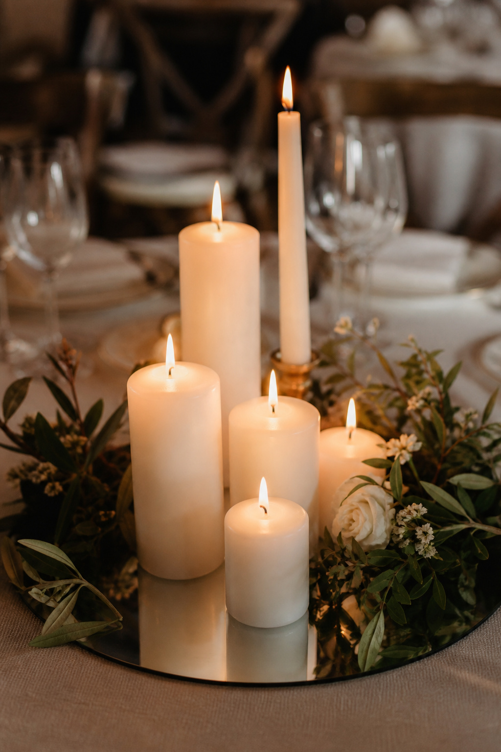 Cluster of pillar and taper candles at varied heights on a mirror