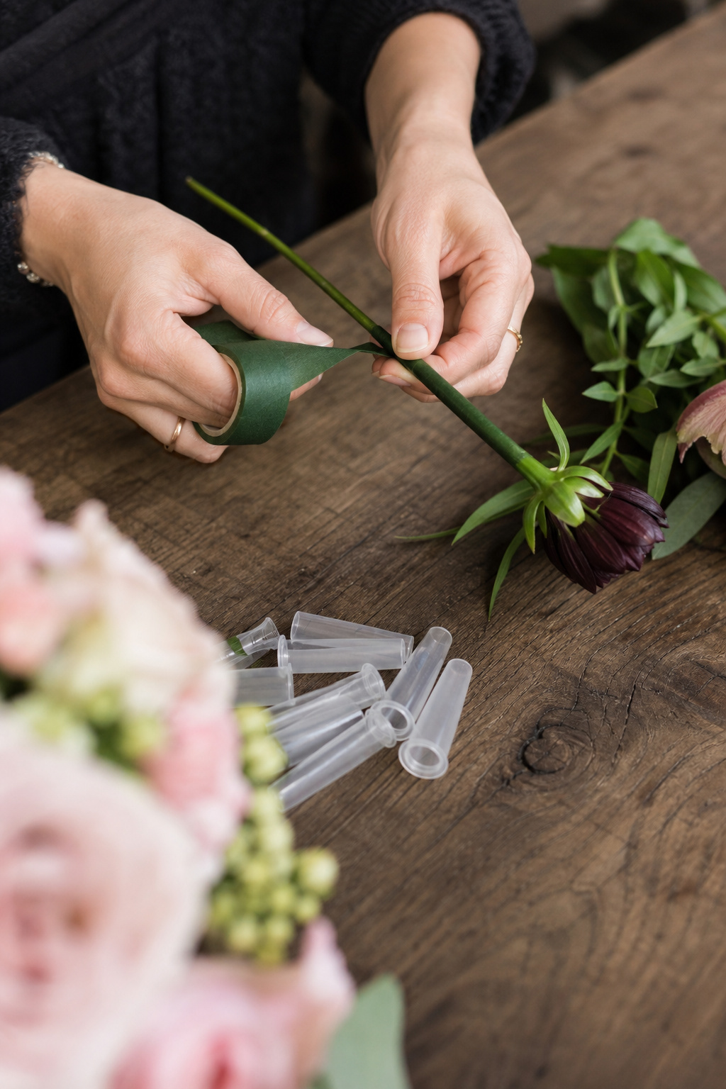 Florist wrapping flower stems with floral tape and water tubes for cake styling