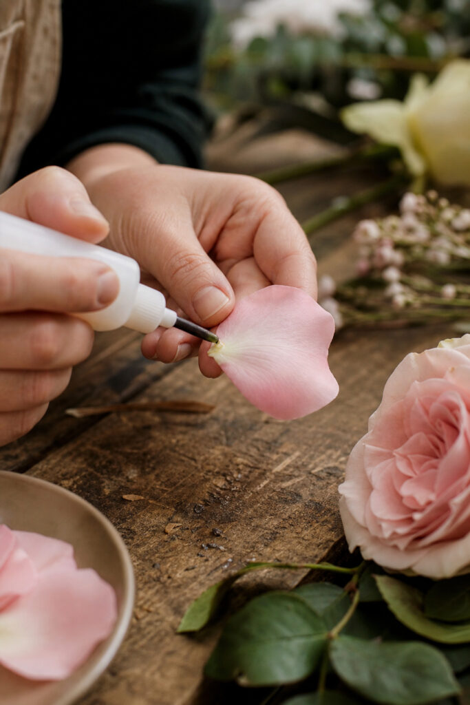 Florist applying cold floral adhesive to a rose petal by hand