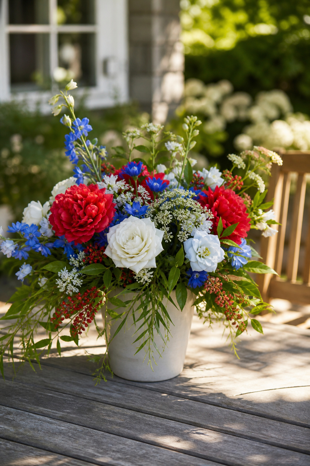 Silk red, white, and blue flowers arranged with real greenery in an outdoor setting
