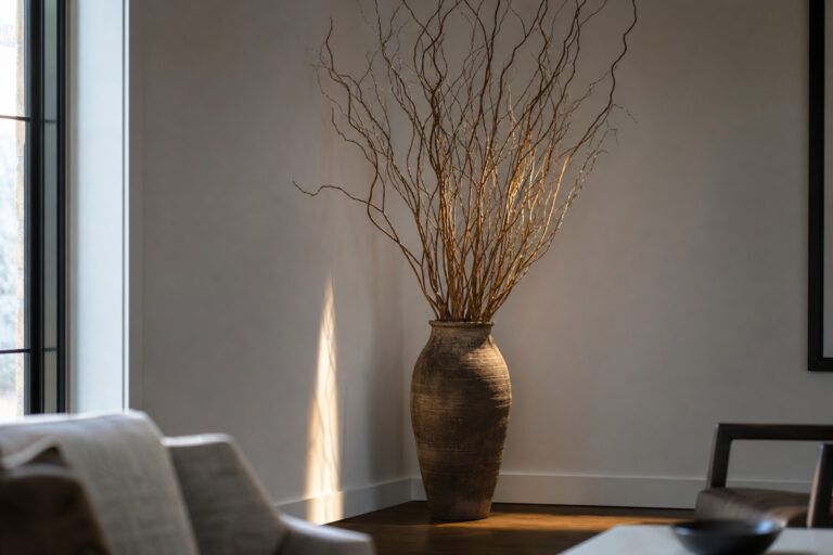 Large ceramic floor vase with curly willow branches in the corner of a contemporary living room