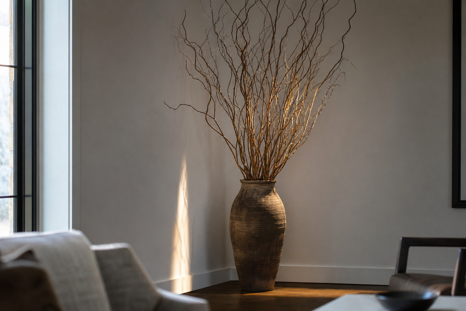 Large ceramic floor vase with curly willow branches in the corner of a contemporary living room
