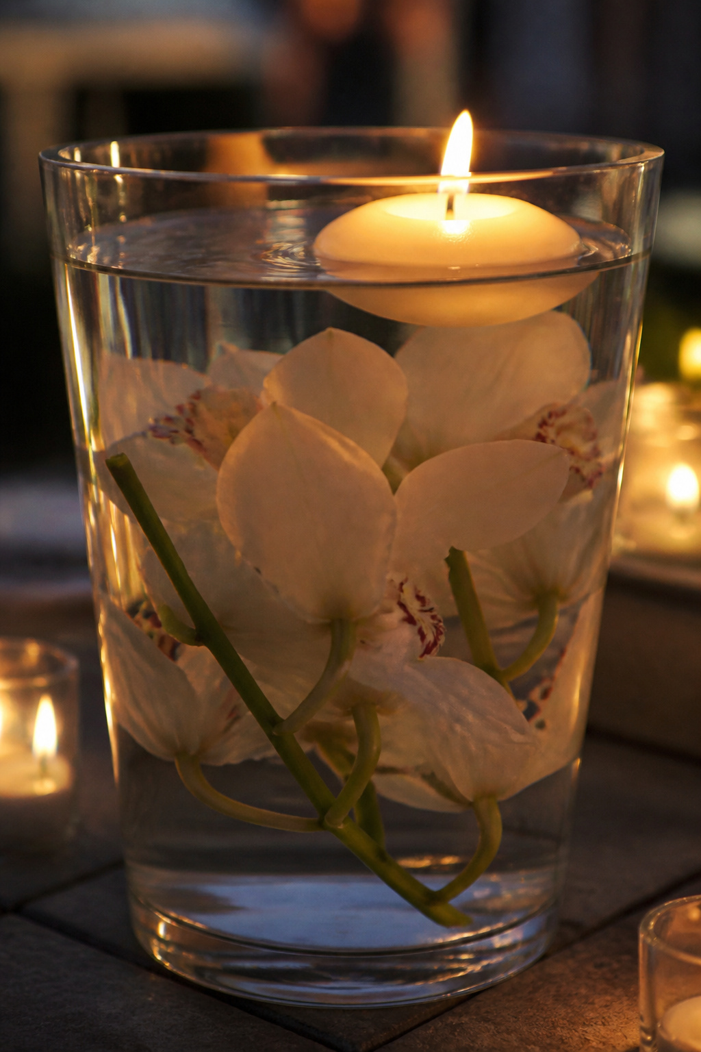 Floating candle glowing above a submerged orchid arrangement at dusk