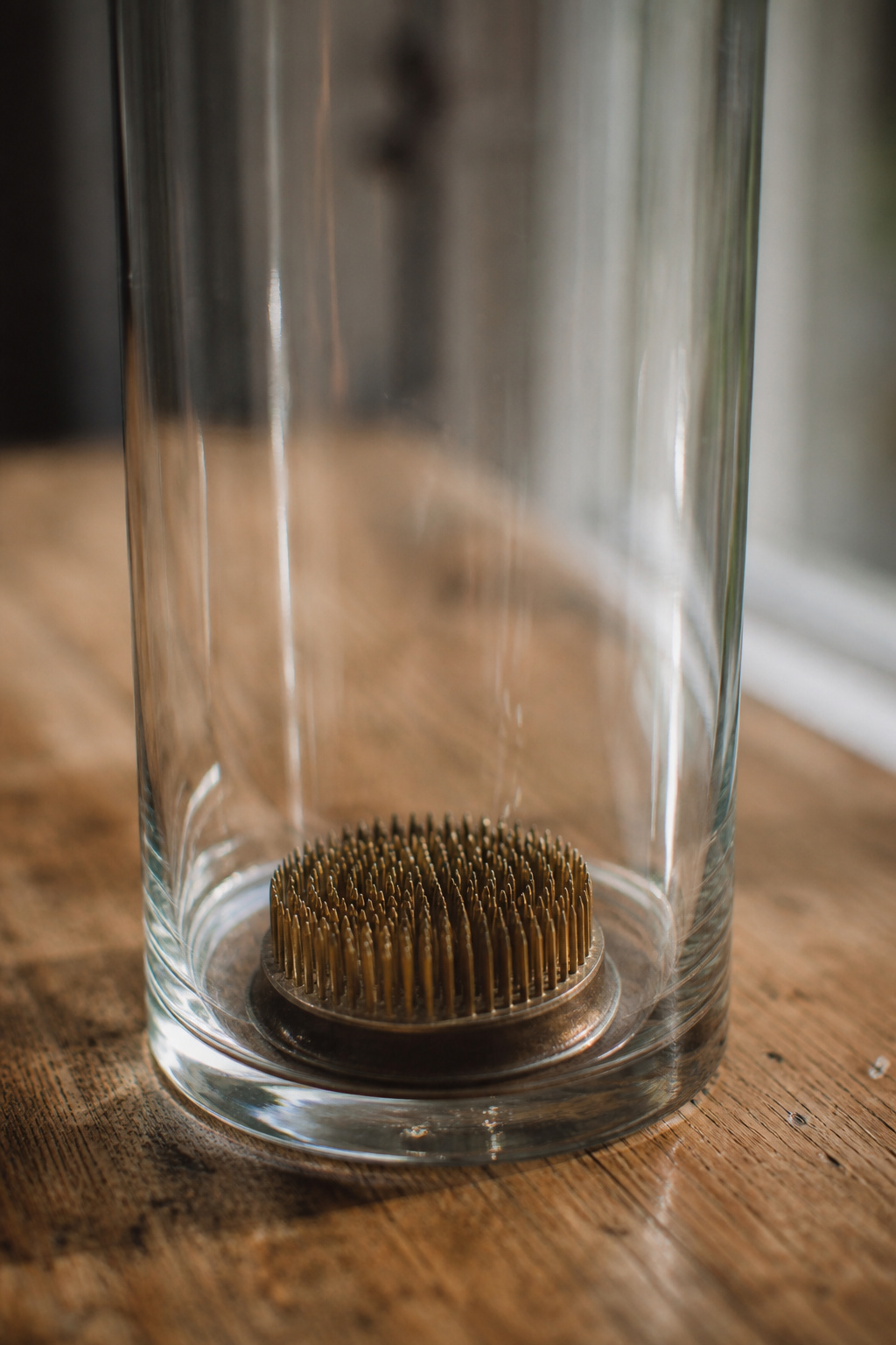 Weighted metal flower frog sitting at the bottom of an empty glass vase