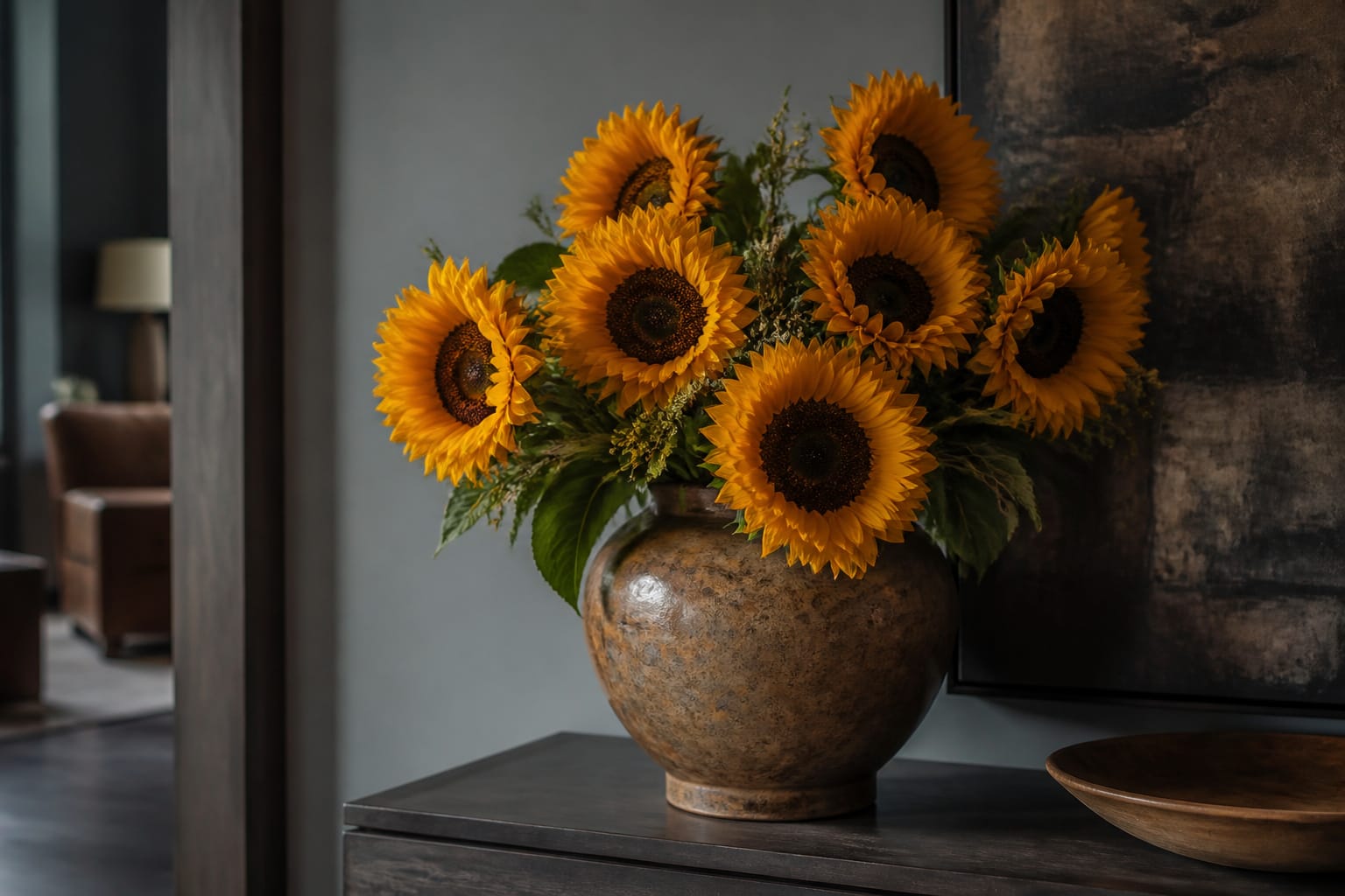 Sturdy wide vase of sunflowers placed in a cool, shaded room