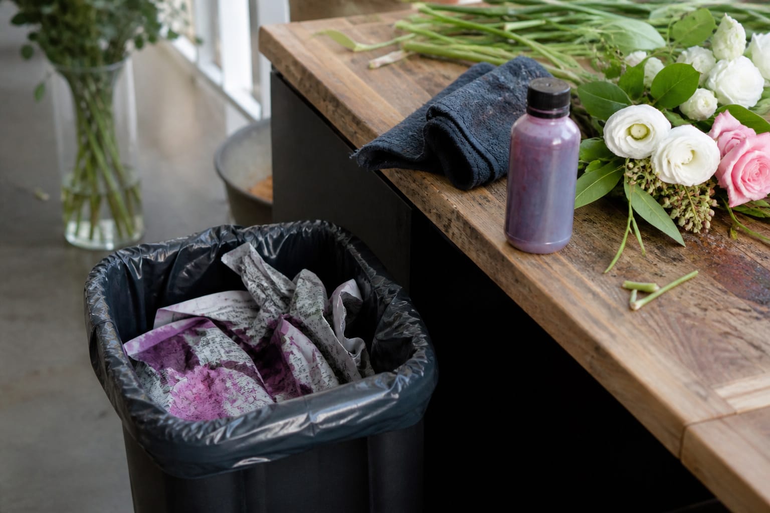 Leftover floral dye absorbed into newspaper for safe disposal beside a worktable