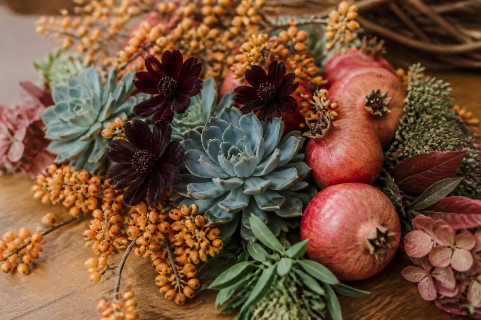 Substitute flowers and berried branches for a fall basket arrangement, including pomegranates and chocolate cosmos