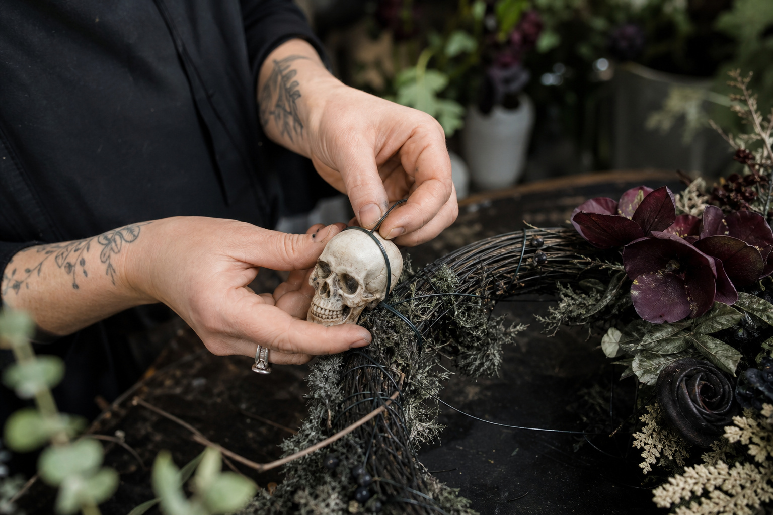 Florist wiring a small skull accent onto a partially built Halloween wreath