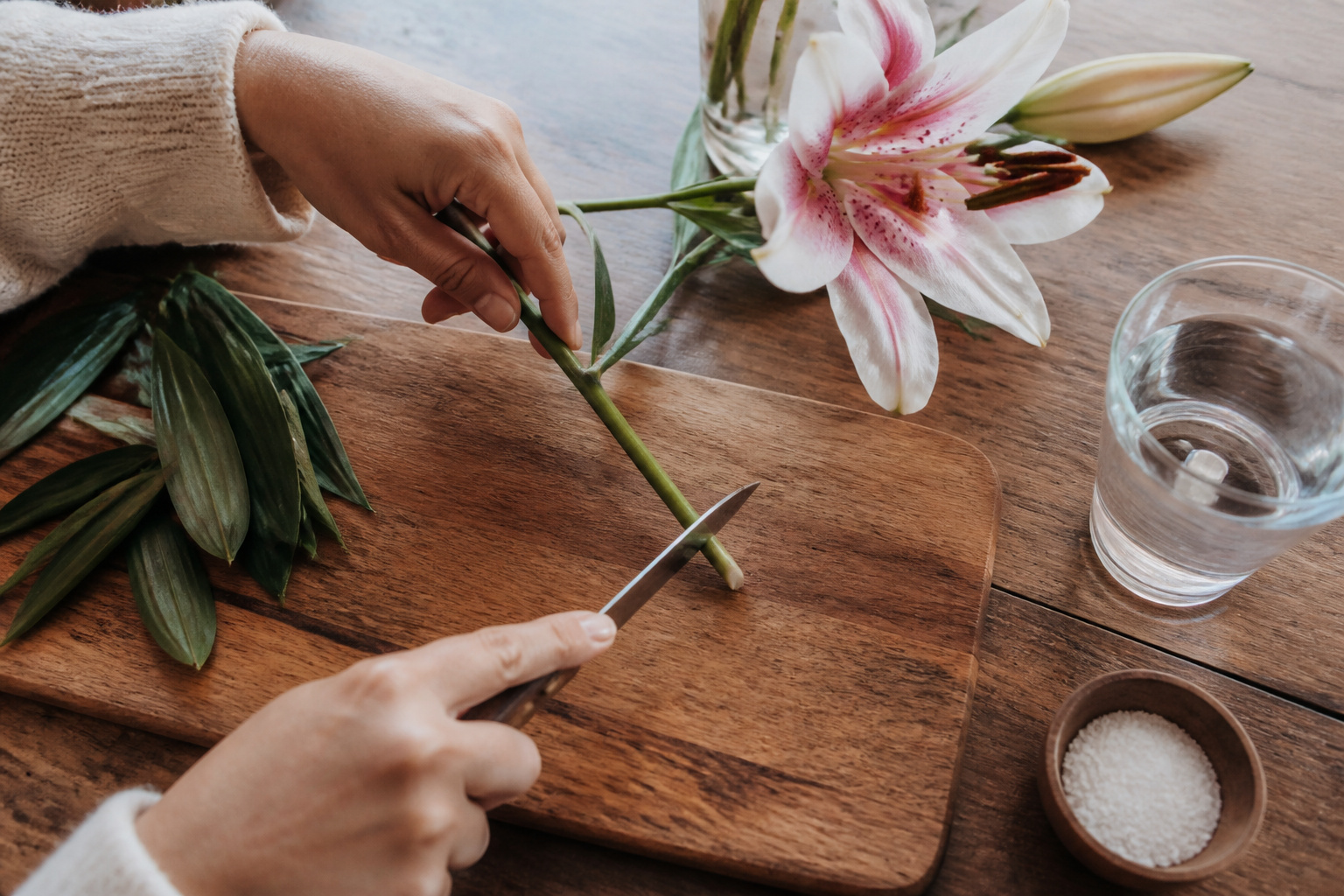 Hands trimming an Oriental lily stem at an angle with a floral knife