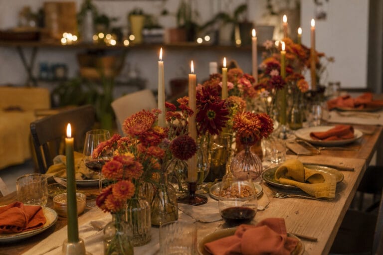Friendsgiving dinner party table with mismatched vases, candlelight, and string lights
