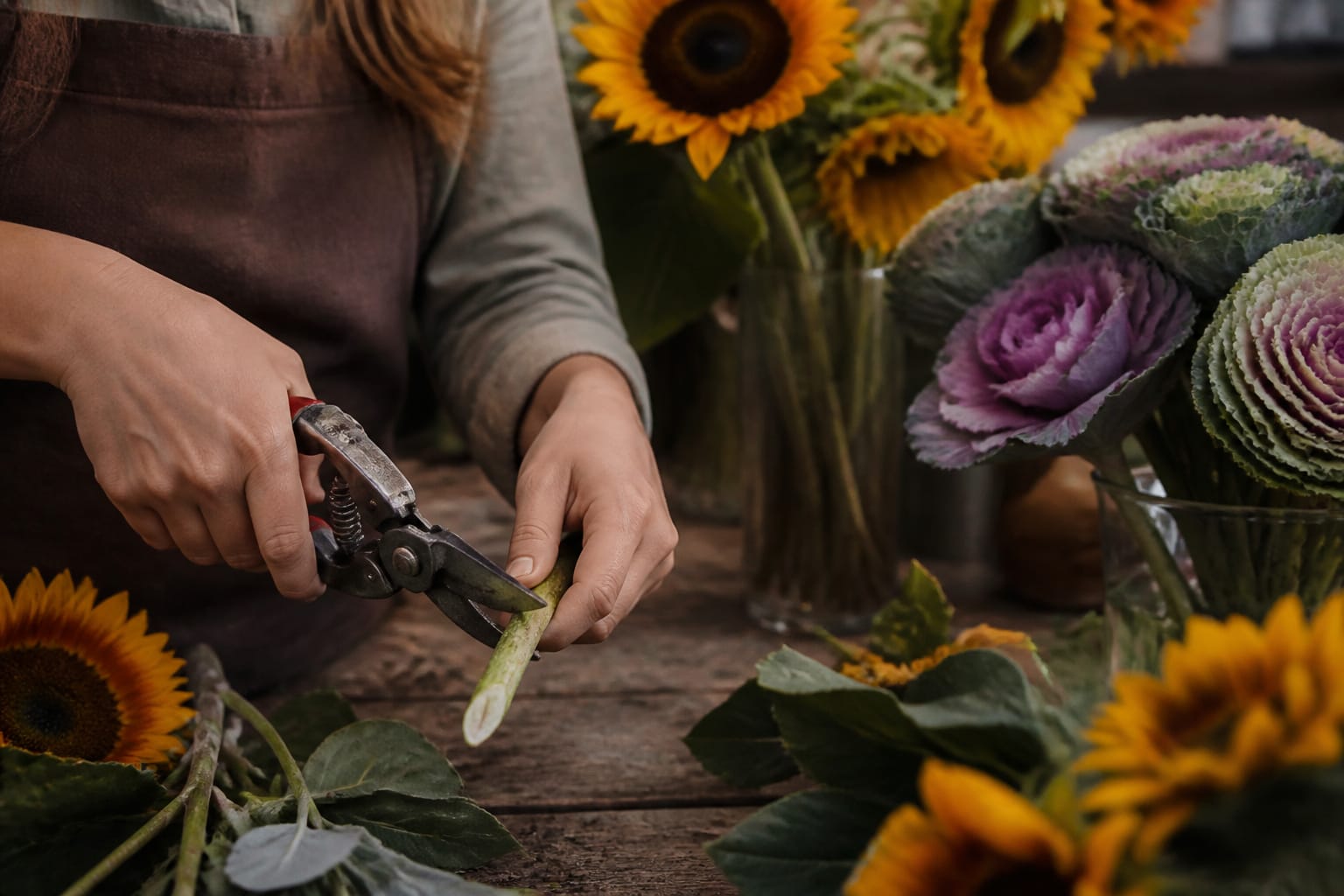 Florist making an arrow-point stem cut on a sunflower for a terraced fall arrangement