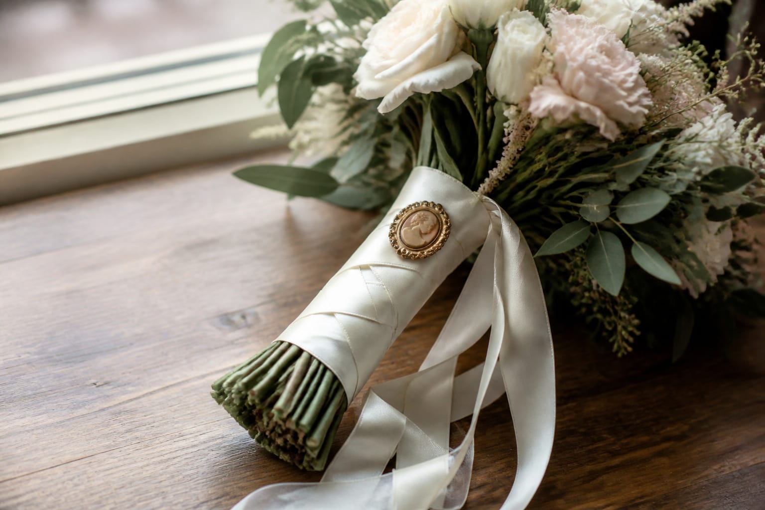Bridal bouquet with an antique cameo brooch and crisscrossed ivory silk ribbon streamers