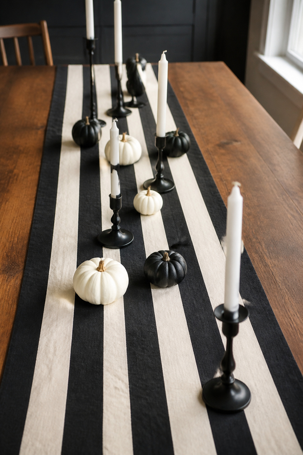 Black and white striped table runner styled with candle holders and mini pumpkins