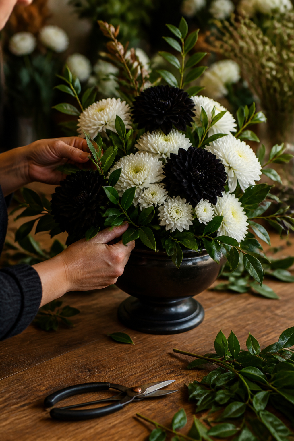 White chrysanthemums and black dahlias arranged in a black ceramic urn