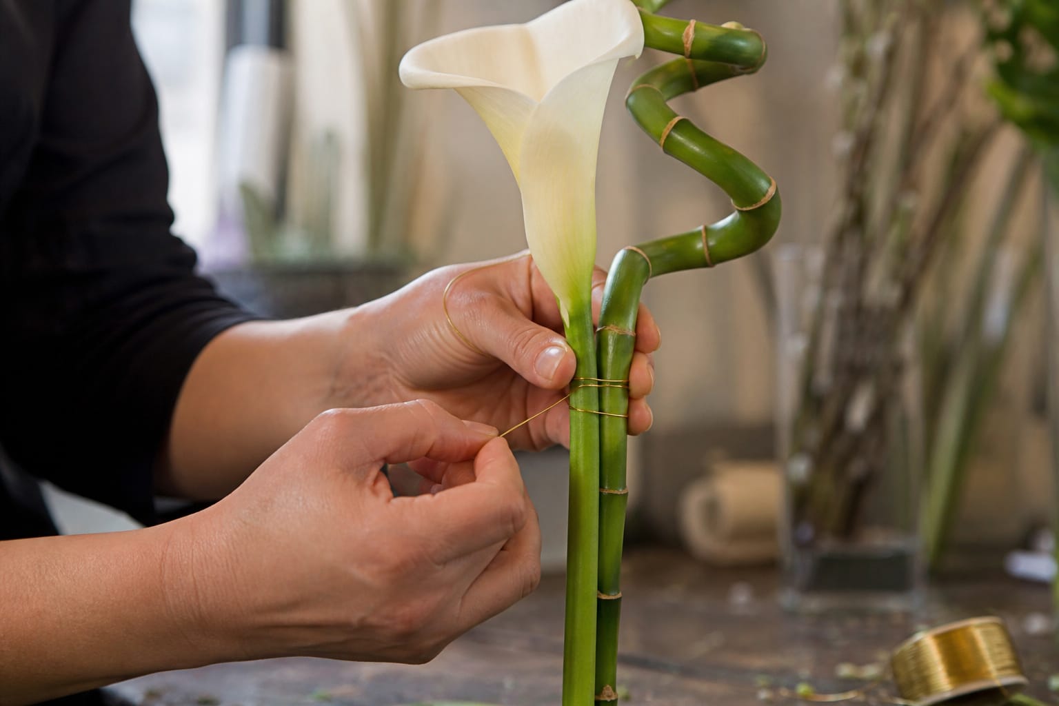 Florist wiring a calla lily stem to spiral bamboo for support