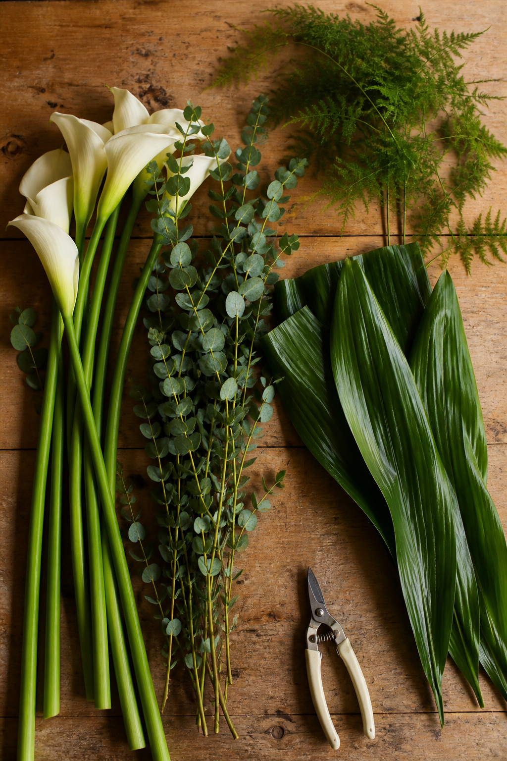 Fresh calla lilies, eucalyptus and aspidistra leaf arranged on a florist worktable