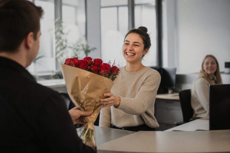 Bouquet of red Valentine's Day roses being delivered to a woman at her office desk