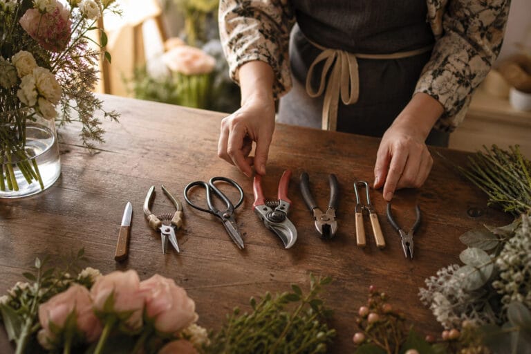 Full set of essential floral design tools laid out on a florist's worktable