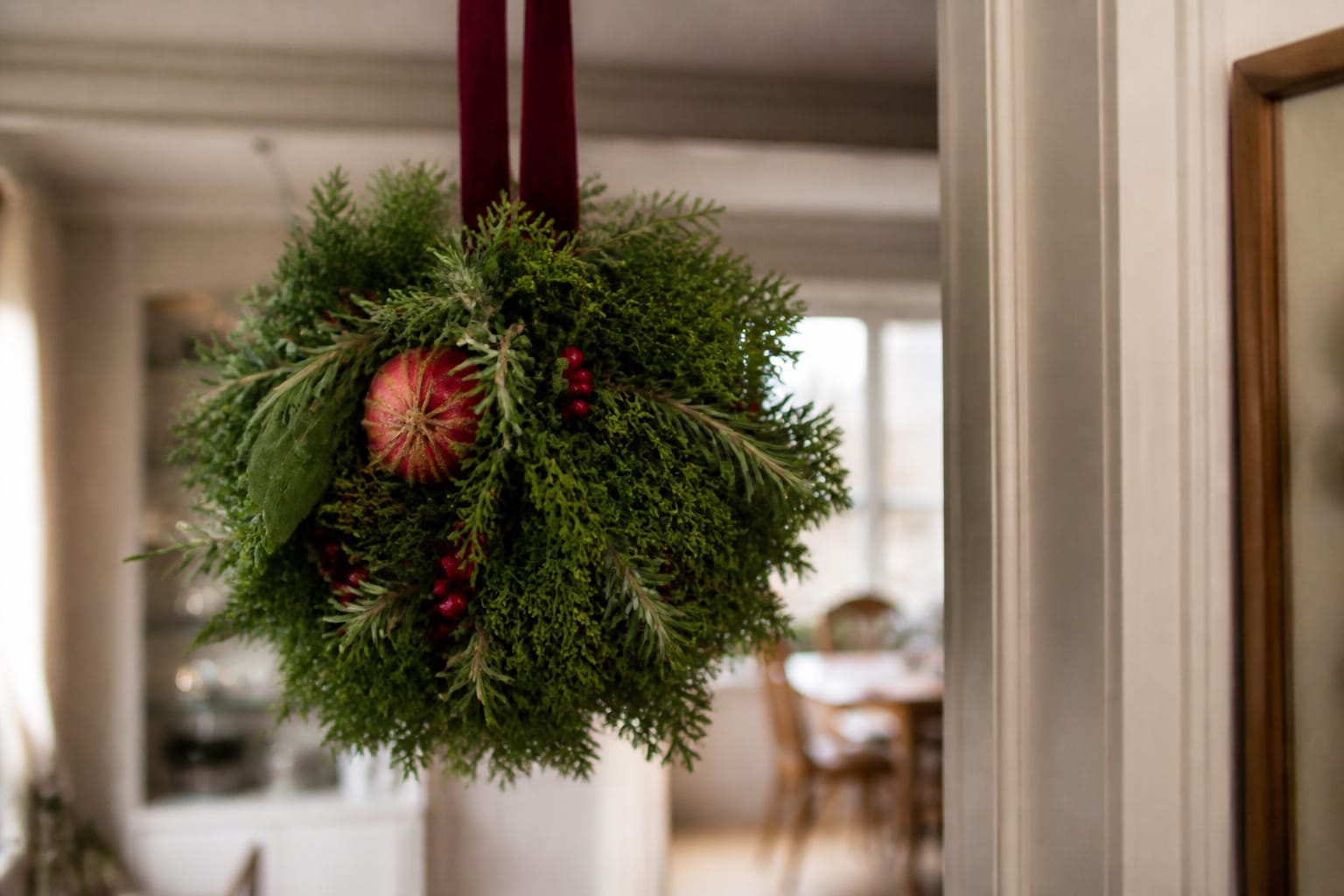 Evergreen Christmas kissing ball hanging in a doorway with a nod to Victorian-era holiday tradition