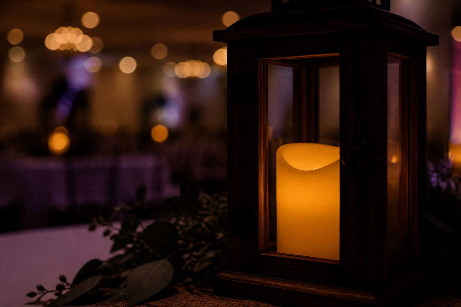 Warm amber flameless candle glowing inside a wooden wedding lantern
