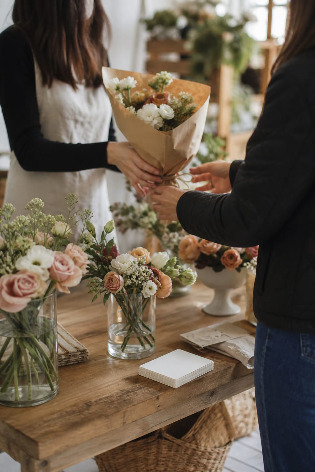 Florist handing a wrapped bouquet to a customer at a local bridal fair table