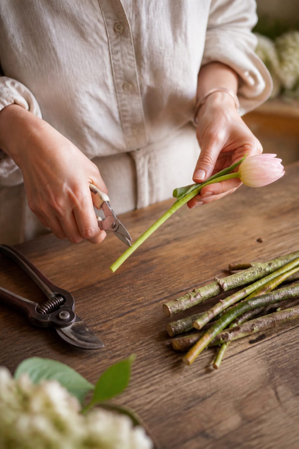 Floral snips cutting a tulip stem at an angle beside a pair of heavier pruners